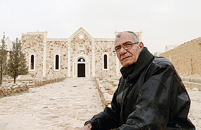 Matanios Dalloul, 62, one of the 20 remaining Christian residents of the central Syrian town of Al-Qaryatain in the Homs province, sits in front of the fifth-century Syriac Catholic monastery of Mar Elian (Saint Elian), damaged by the Islamic State group (IS), who seized the town in 2015.