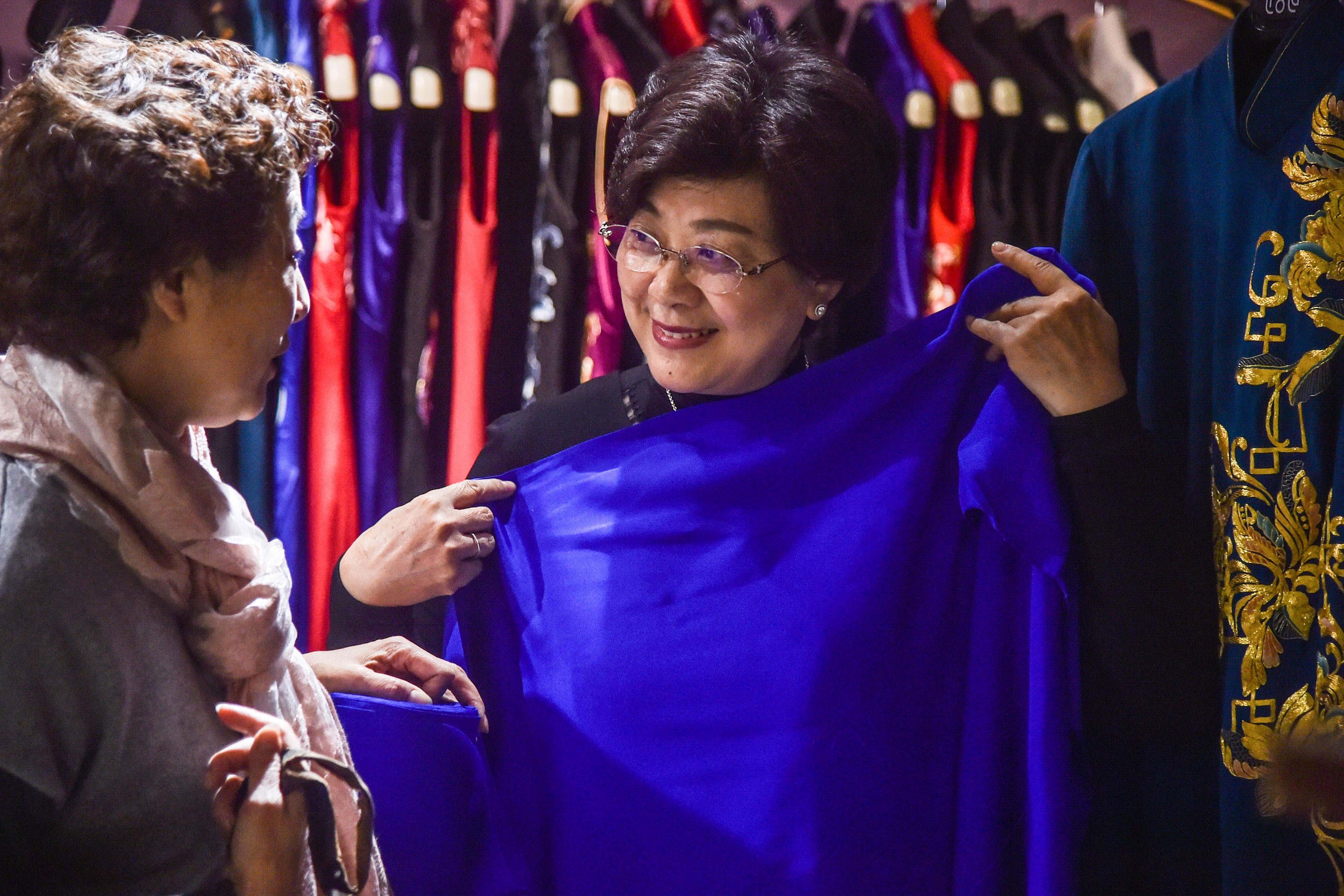 This photo shows a customer (right) trying on a piece of fabric for her custom-made Qipao with a tailor at a Qipao studio in Shanghai.<br>