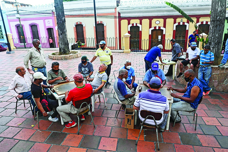 Elderly people play dominoes in tables set up at the Plaza Bolivar of the Petare neighborhood in Caracas.<br>