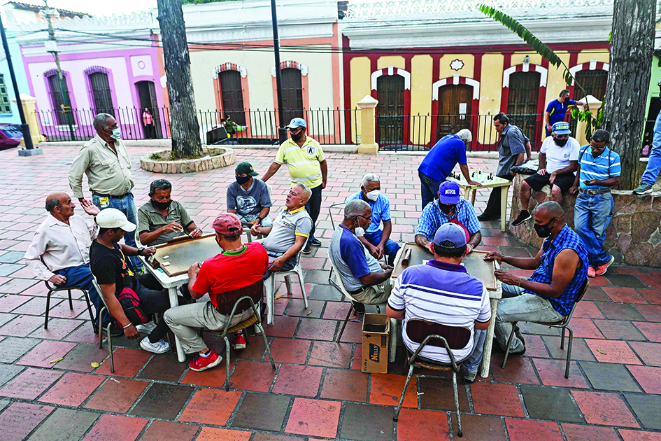 Elderly people play dominoes in tables set up at the Plaza Bolivar of the Petare neighborhood in Caracas.<br>