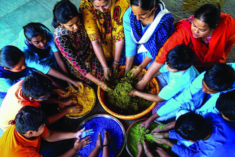 School students along with their teachers take part in preparing herbal colors inside the premises of a school ahead of Holi celebrations.<br>