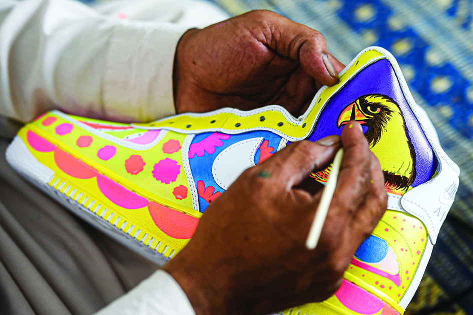 Truck artist Haider Ali works on a pair of sneakers at his workshop in Karachi.<br>