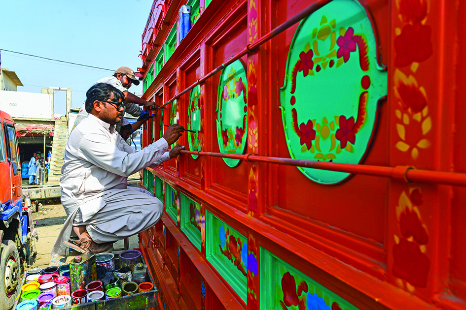 Artist Haider Ali (right) works on a truck at a workshop in Karachi.<br>