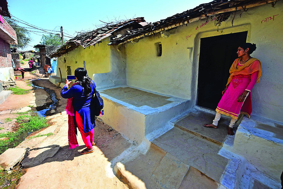Geeta Devi makes a video with her phone during an interview with a woman who she says was abandoned by her husband, while reporting in Banda district, Uttar Pradesh state. <br>