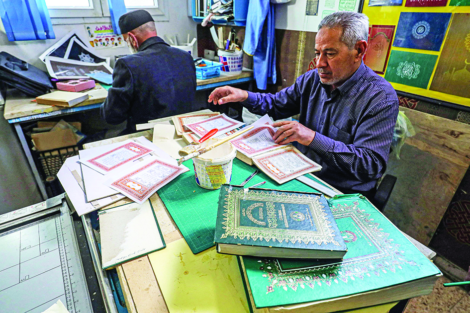 Libyan restorer of the Holy Quran Khaled Al-Drebi (right), assembles pages together to be glued into a volume during a workshop on the restoration of copies of Islam's holy book.