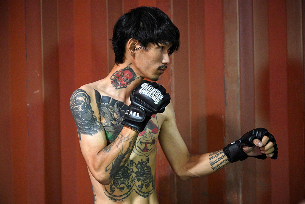 This photo shows a fighter posing as he has his photo taken at an event by Fight Club Thailand.