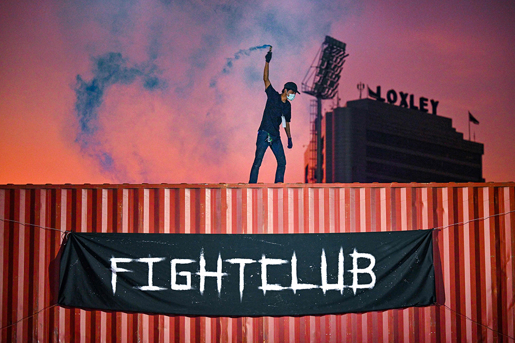 This photo shows a man lighting a flare on top of a shipping container at an event by Fight Club Thailand.