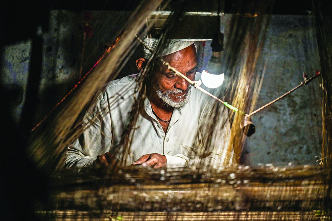 A worker uses a hand loom to weave a Banarasi silk sari at a workshop in Varanasi.