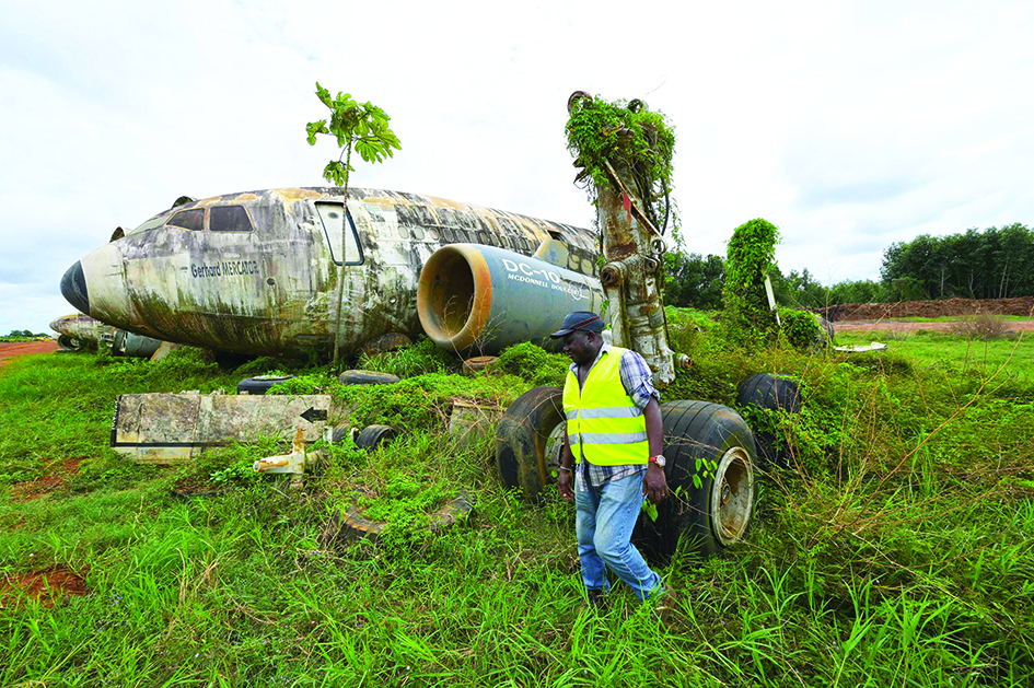 An employee of Aziz Alibhai walks past wreckage of airplanes that are displayed on the edge of a landing strip.