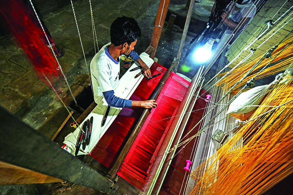 A worker uses a hand loom to weave a Banarasi silk sari at a workshop in Varanasi.