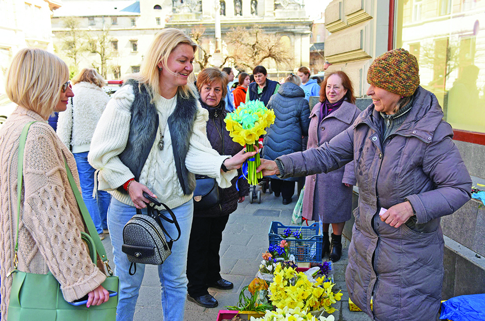 Olga Fityo-Styslo (right) shows shows off her daffodils, some of them dyed blue, to customers at the market in the western city of Lviv. 