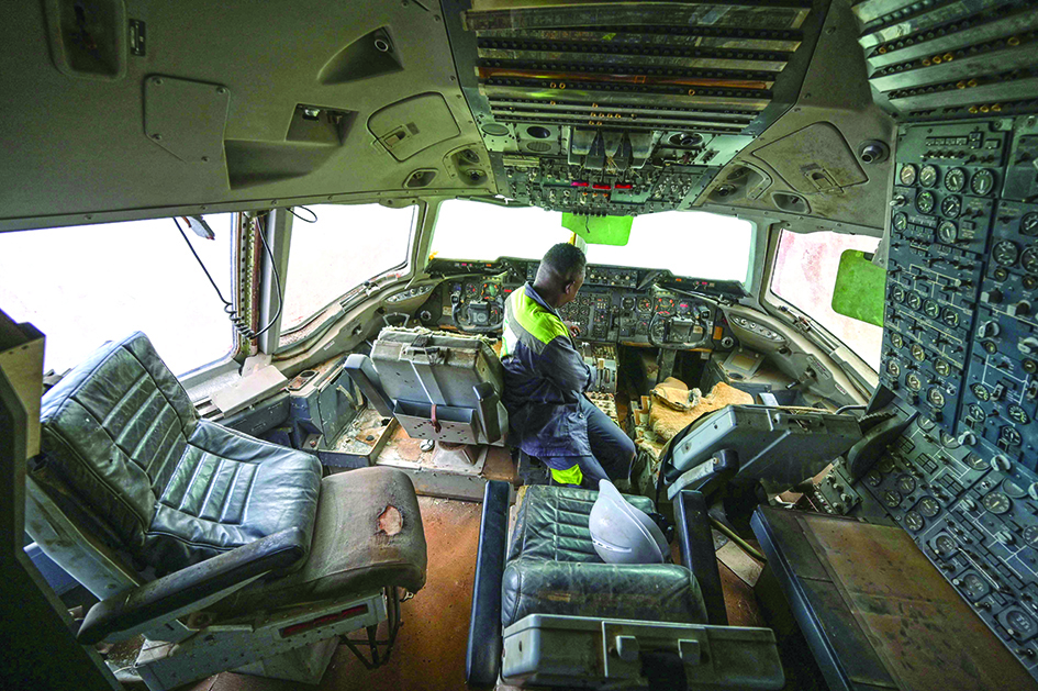 An employee of Aziz Alibhai is seen in the wreckage of a cockpit in a DC-10 aircraft that is displayed on the edge of a landing strip. 
