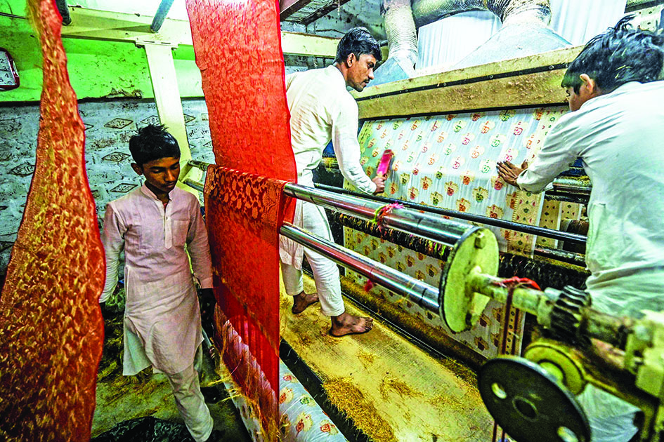 Workers give final touches to a Banarasi silk sari at a workshop in Varanasi.