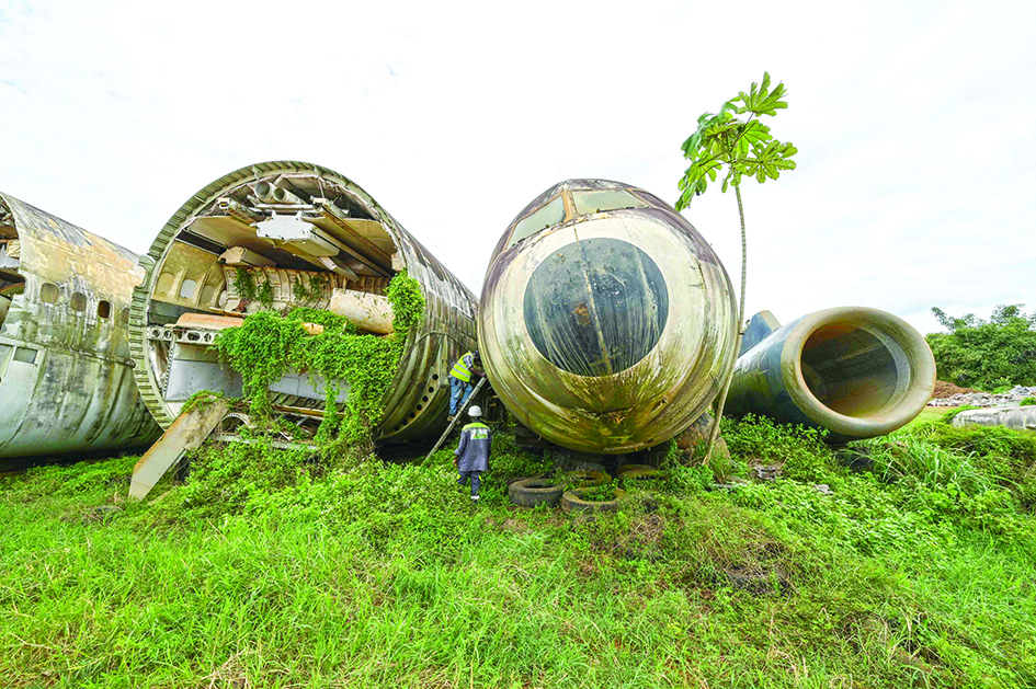 An employee of Aziz Alibhai climbs into the wreckage of an airplane that is displayed on the edge of a landing strip.