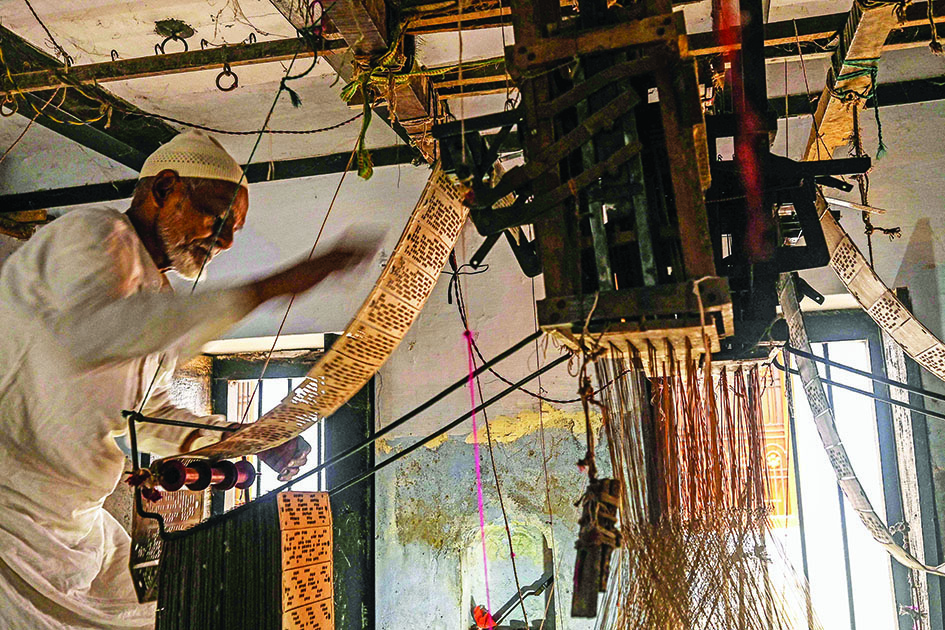 A worker adjusts his hand loom before weaving a Banarasi silk sari at a workshop in Varanasi.