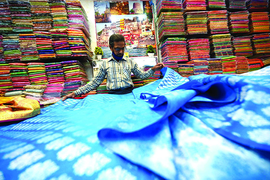 A shopkeeper shows a traditional Banarasi sari at a store in Varanasi.