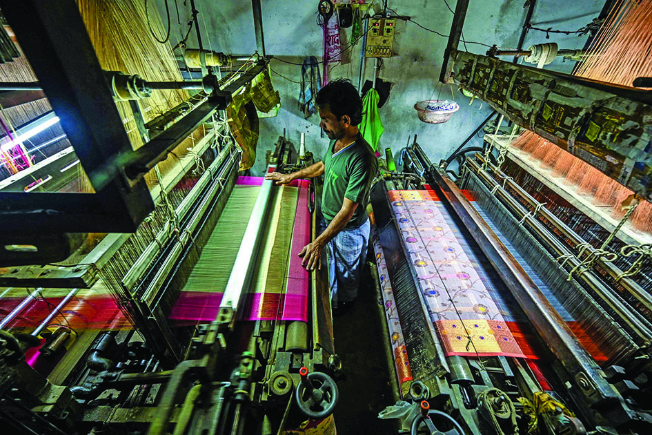 A worker uses a power looms to weave a Banarasi silk sari at a workshop in Varanasi.