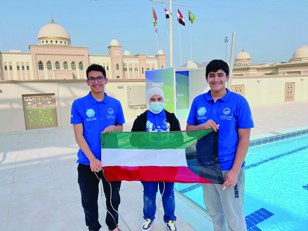 Members of the Kuwaiti Team Blue Tech Youth Valley hold Kuwait's flag.