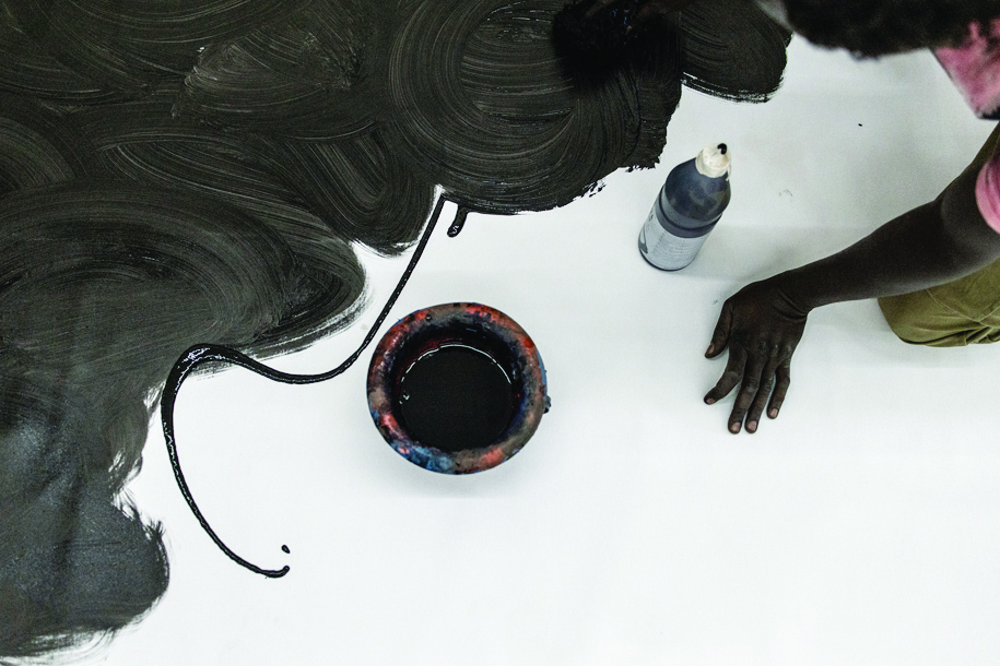 Contemporary Senegalese artist, Omar Ba, paints onto a black canvas at his workshop.