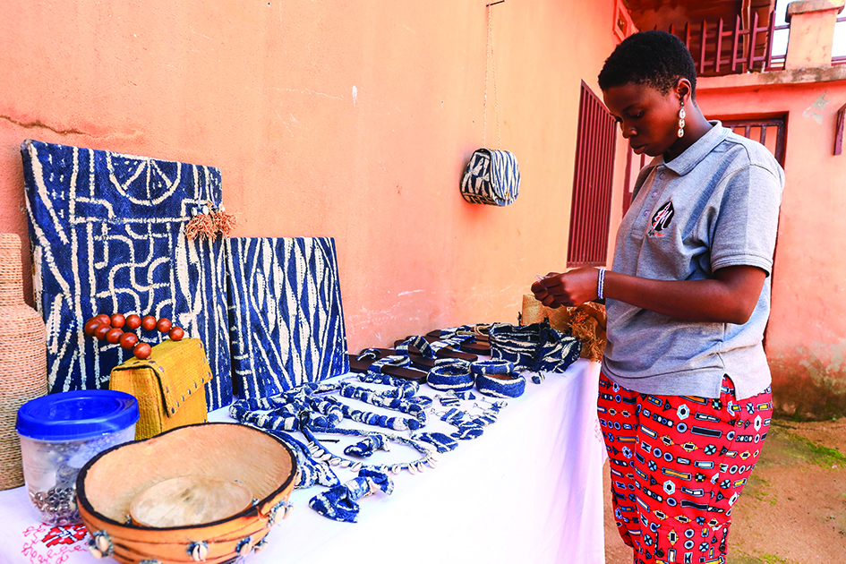 Yougo Teguia Doriane, 24, a creative stylist, decorates her stand with products made with ndop fabric at a market in Bafoussam.
