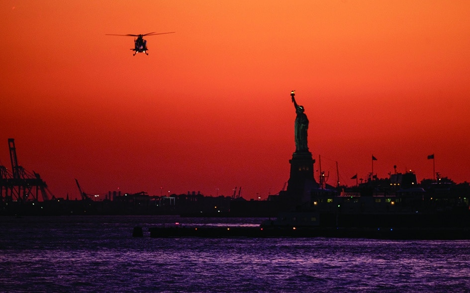 In this file photo a helicopter flies past the Statue of Liberty as the sun sets in New York City. 