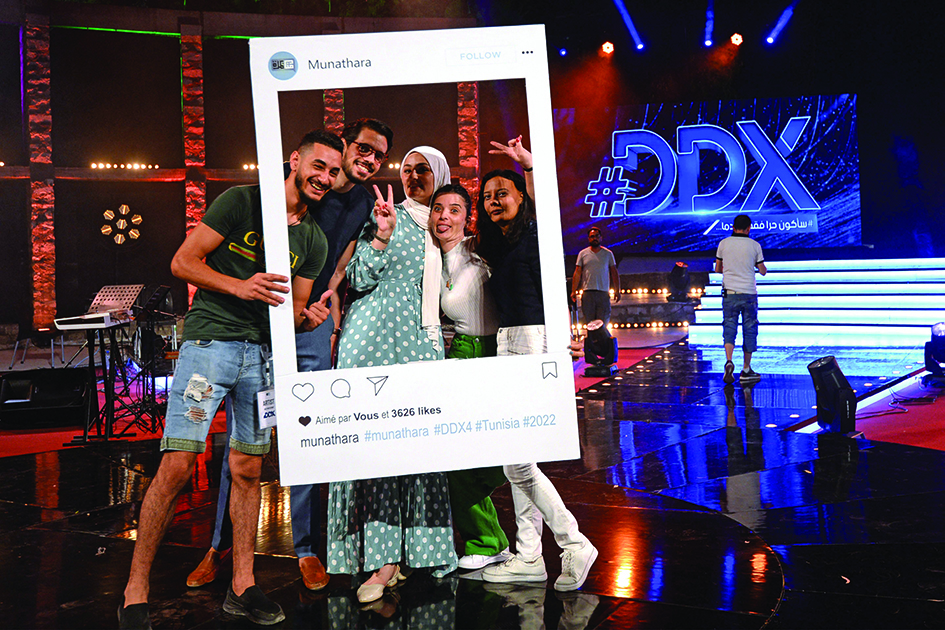 Participants pose for a photo with a cutout frame depicting an Instagram social media post on the set of the #DDX talent show.