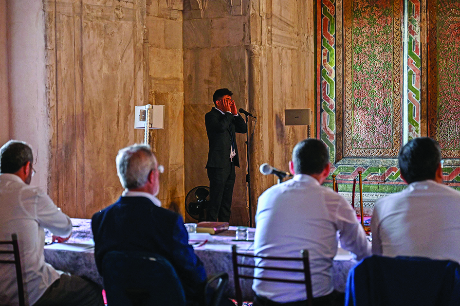 A Turkish muezzin performs the Ezan call to prayer in front of a jury, inside Old mosque (Eski Camii) in Edirne.