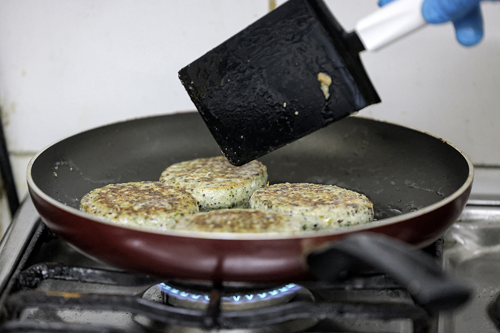 A worker cooks salicornia plant-based burger patties in a pan at a food processing plant in the Gulf emirate of Sharjah.