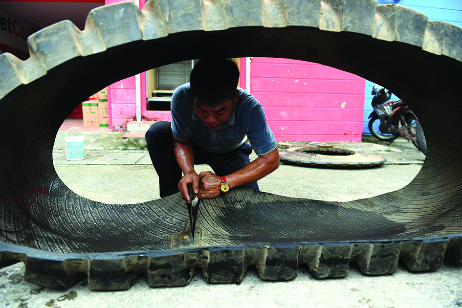 This photo shows worker cutting apart a rubber truck tyre outside a workshop in Hanoi.
