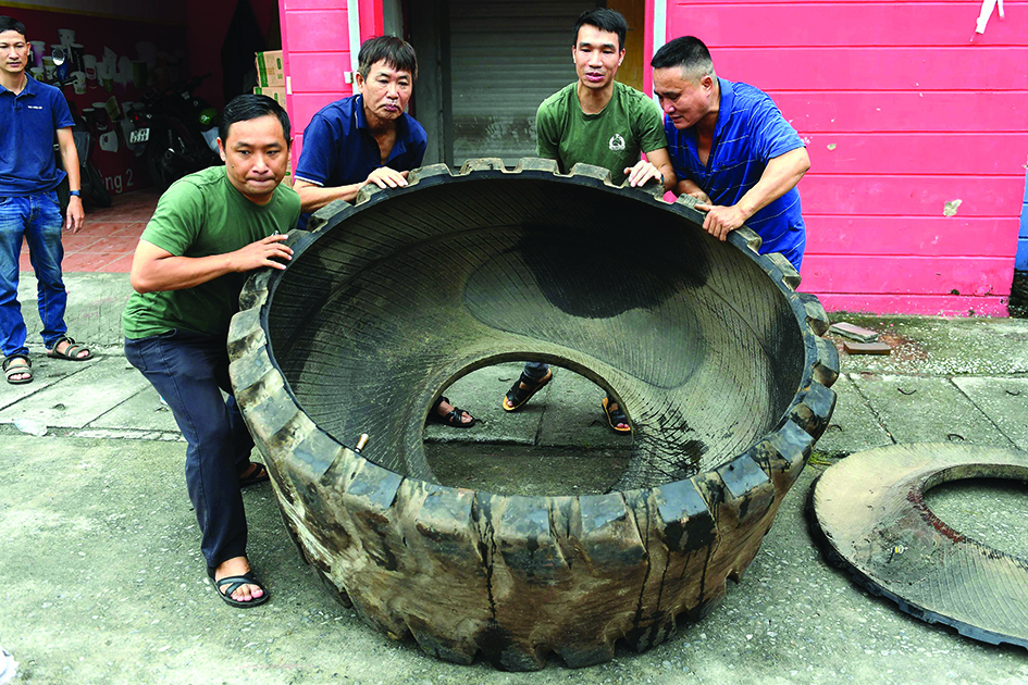 This photo shows workers overturning a truck tyre outside a workshop in Hanoi, before it's transformed into rubber sandals.