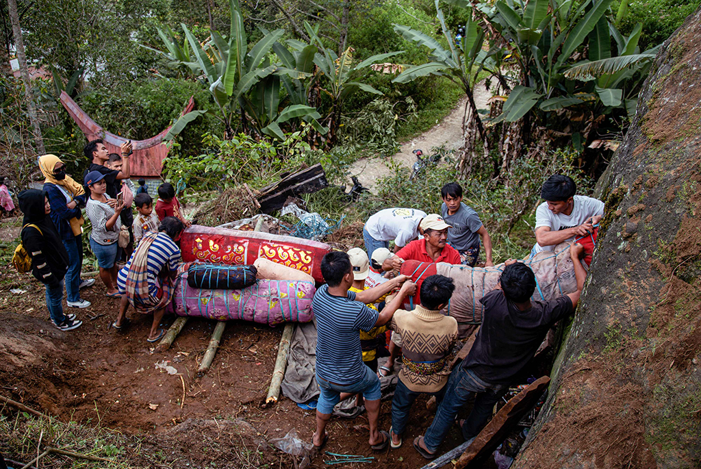This picture shows members of the Toraja ethnic group exhuming bodies of their relatives from a community burial site (right), to be cleaned and dressed in a series of traditional ceremonies honoring the dead known as