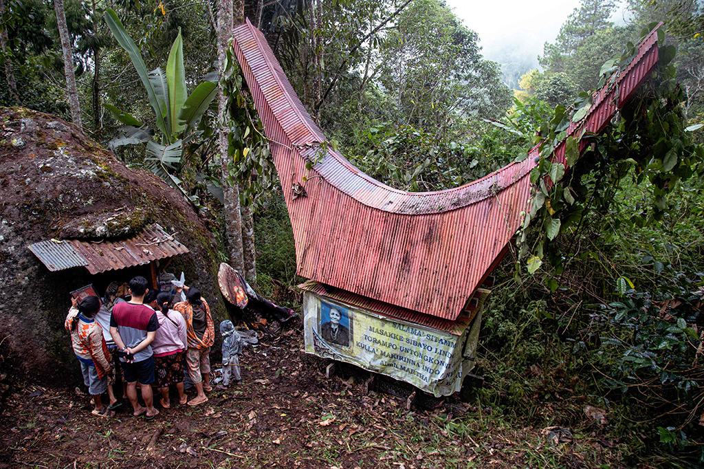 Members of the Toraja ethnic group exhuming bodies of their relatives from a community burial site (left), to be cleaned and dressed in a series of traditional ceremonies honoring the dead known as