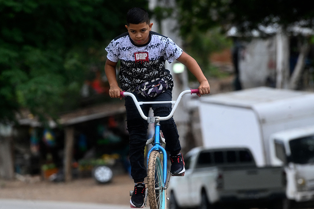 Eduardo Espinal, a 12-year-old child, rides on a bike to his barbershop in Comayagua, Honduras.