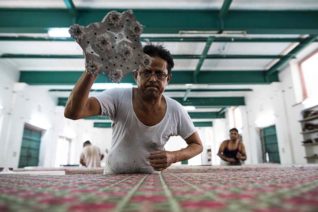 A worker uses the hand block printing technique on a cotton fabric.