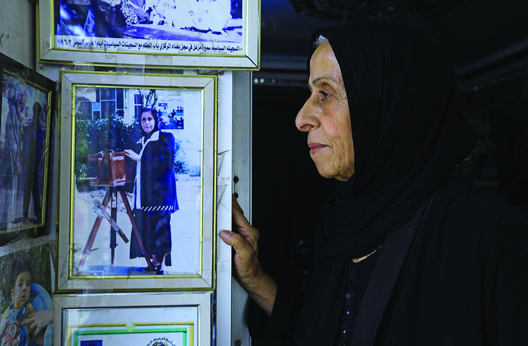 Iraqi photographer Samira Mazaal poses for a picture next to framed images retracing her career during an interview.