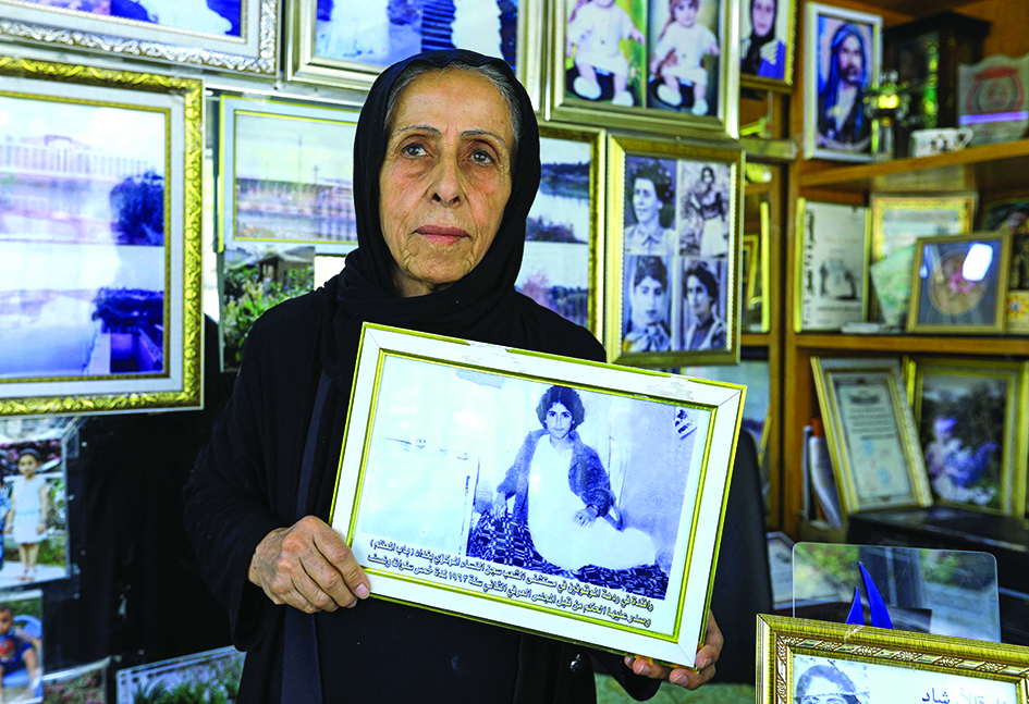 Iraqi photographer Samira Mazaal poses with a framed picture of her on a hospital bed after being tortured in a building in Amarah.