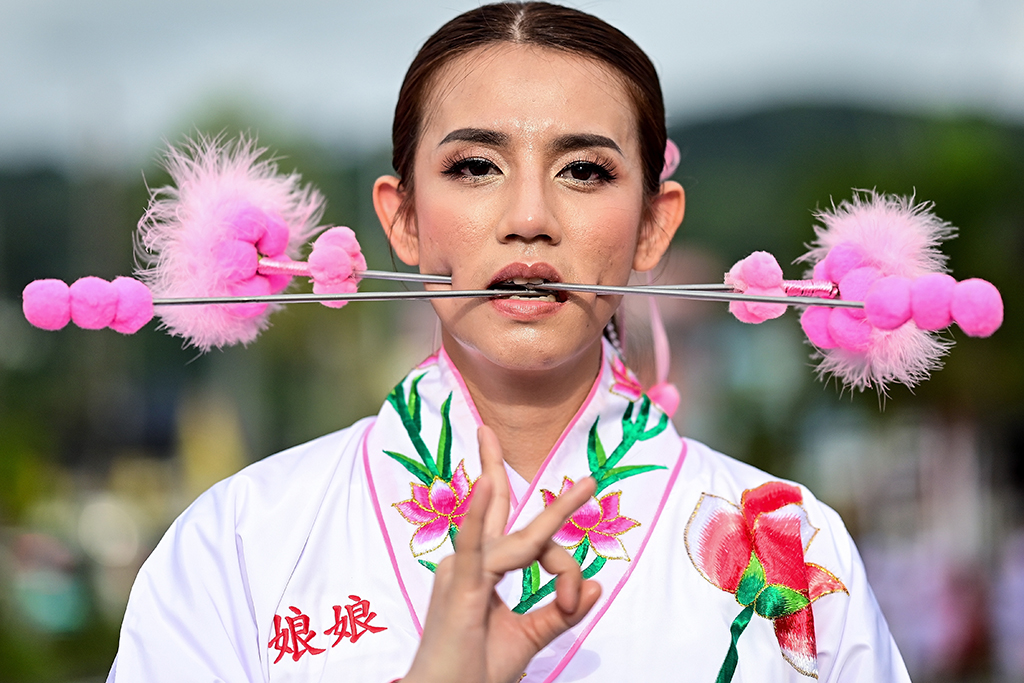 A devotee of the Jor Soo Gong Naka shrine with skewers pierced through her cheeks takes part in a procession during the annual Vegetarian Festival in Phuket.