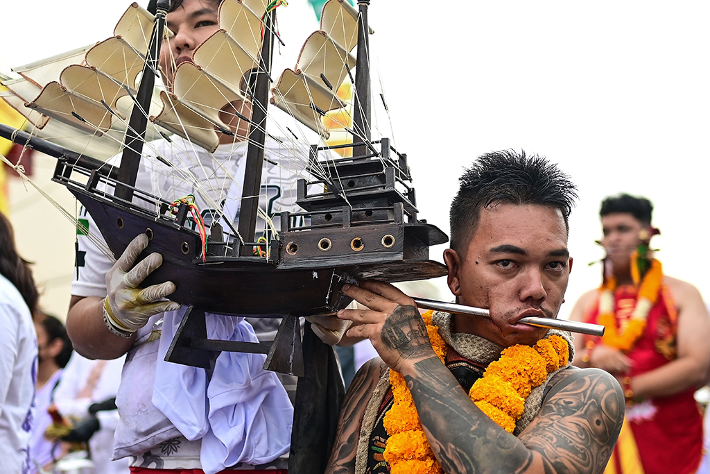 A devotee of the Jor Soo Gong Naka shrine with a ship model pierced through his cheek waits to take part in a procession during the annual Vegetarian Festival. 