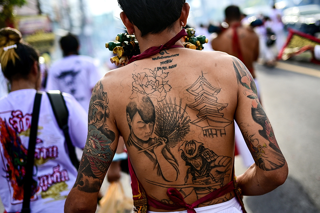 Tattoos are seen on the back of a devotee with skewers pierced through his cheeks at a procession during the annual Vegetarian Festival.