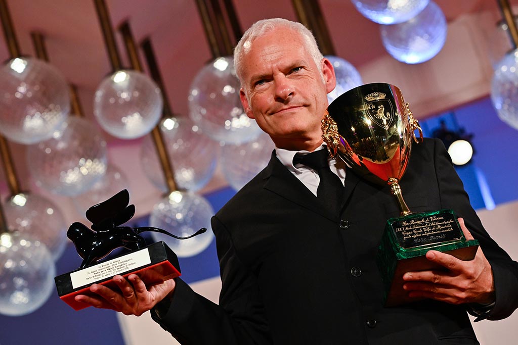 British director Martin McDonagh poses with the Award for Best Screenplay (left) and the Coppa Volpi for Best Actor he received on behalf of Irish actor Colin Farrell, for 