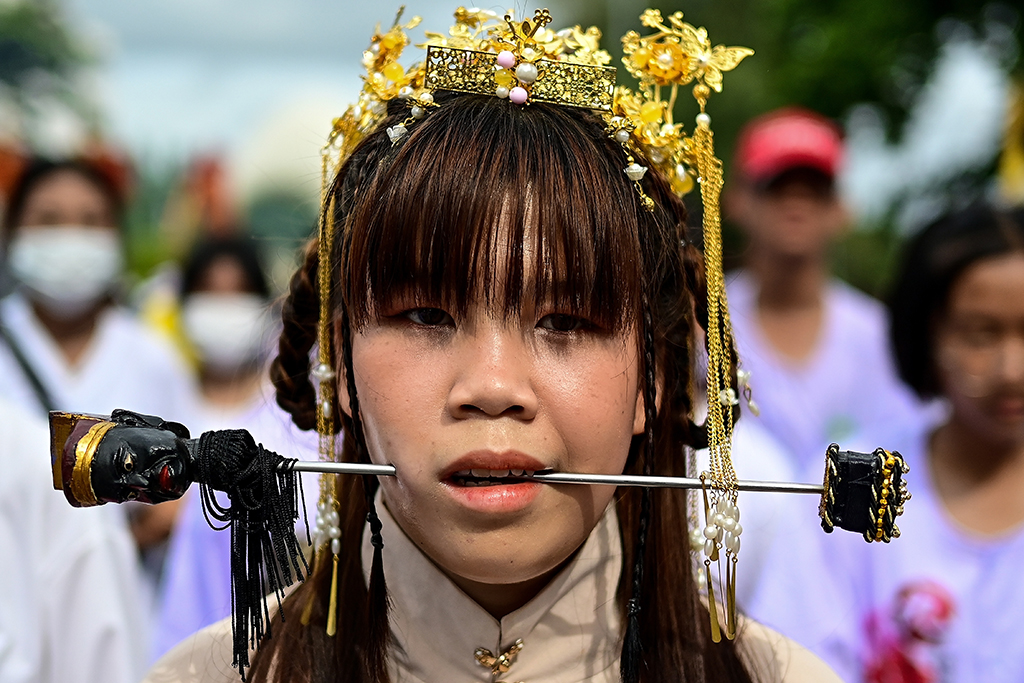 A devotee of the Jor Soo Gong Naka shrine with a skewer pierced through her cheek takes part in a procession during the annual Vegetarian Festival.