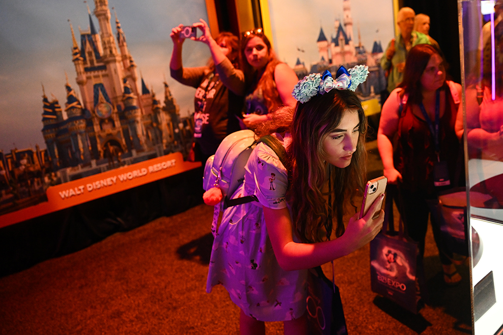 An attendee takes pictures of exhibits during the Walt Disney D23 Expo.