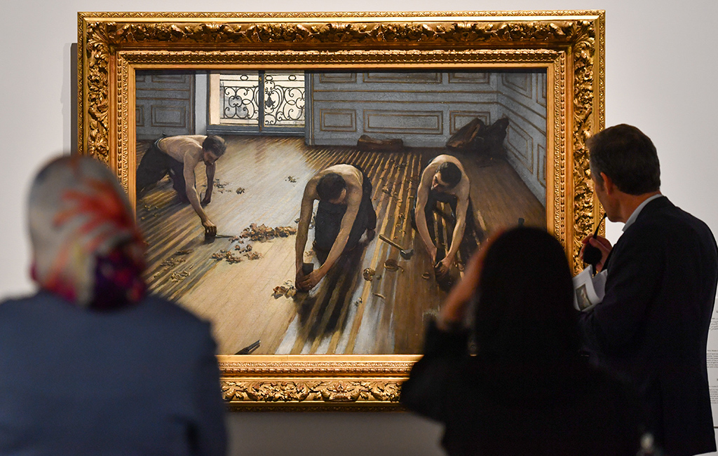 Visitors look at Gustave Caillebotte's masterpiece Floor Scrapers.