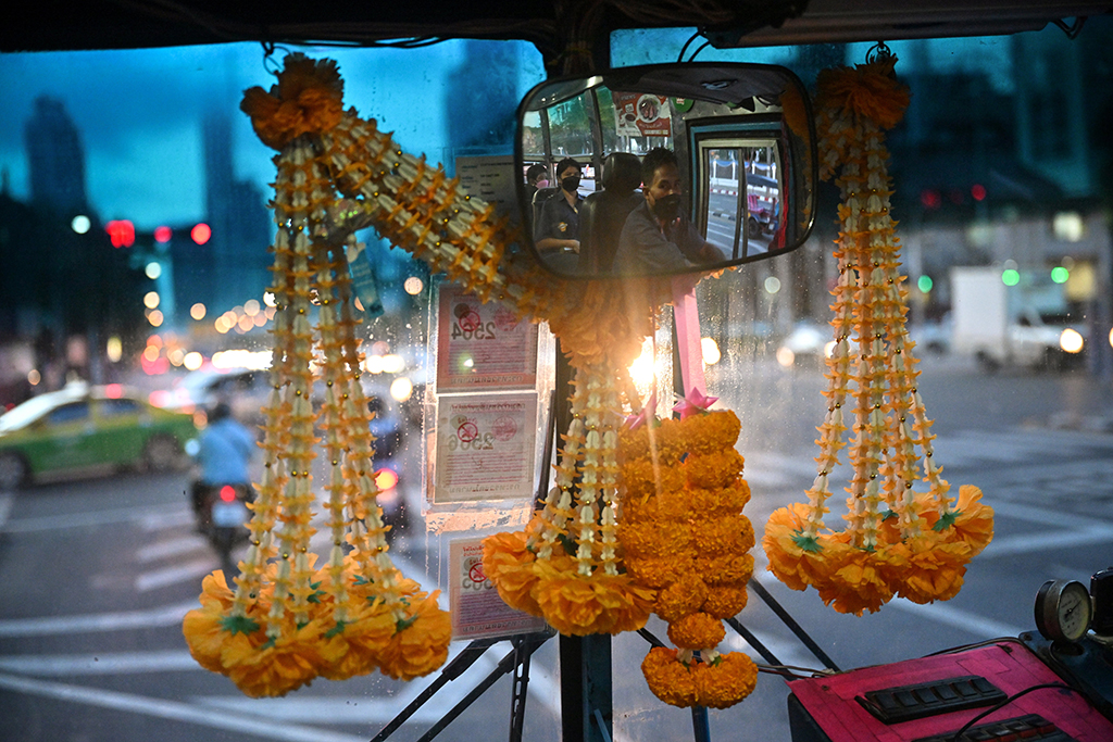 Bus driver Aphisak “Boy” Sodmui and his wife, bus conductor Arunee On-Sawats, behind him in the mirror as he drives the No.8 bus in Bangkok.