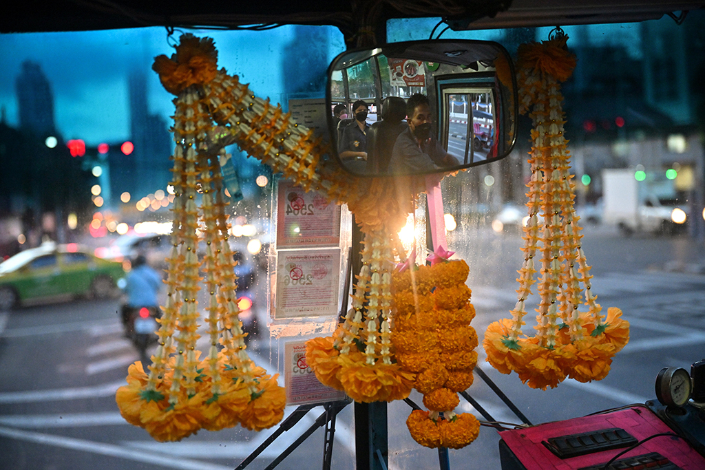 Bus driver Aphisak “Boy” Sodmui and his wife, bus conductor Arunee On-Sawats, behind him in the mirror as he drives the No.8 bus in Bangkok. 