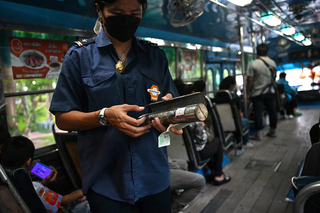Bus conductor Arunee On-sawats collecting the fare from passengers on the No.8 bus in Bangkok.