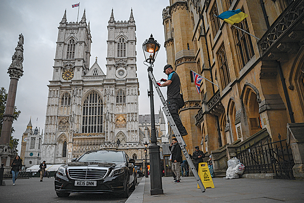 A British Gas engineer attaches a stepladder to a gas-powered lamp before servicing it, near Westminster Abbey in central London.