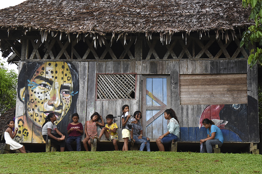 Tikuna indigenous young people chat by a house in San Martin de Amacayacu, Colombia.