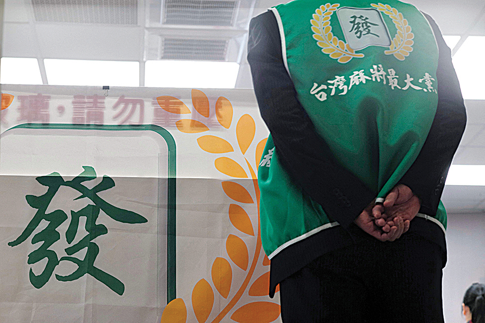 An employee wearing a vest showing the logo of the Mahjong the Greatest party, at a mahjong parlor in Kaohsiung.