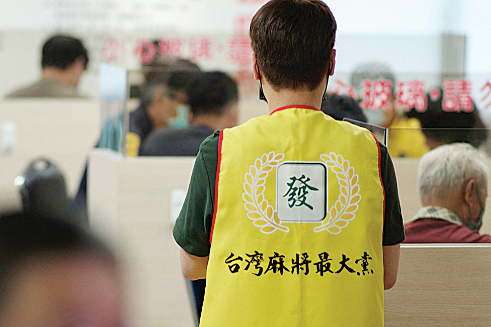 An employee wearing a vest showing the logo of the Mahjong the Greatest party, at a mahjong parlor in Kaohsiung.